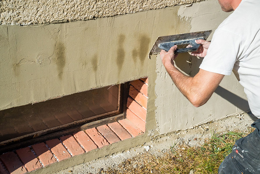Plasterer completing render work on a exterior wall of a house
